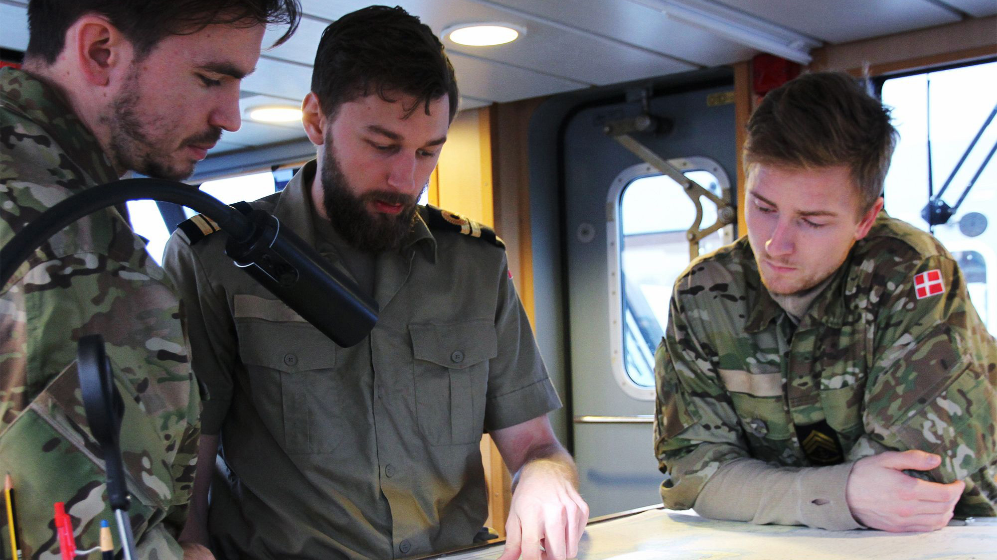 To sergenter i sørværnet kigger på en kort på skibet