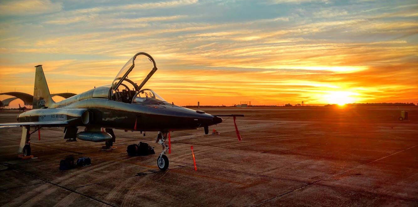 Kampfly står på jorden med solnedgangen i baggrunden