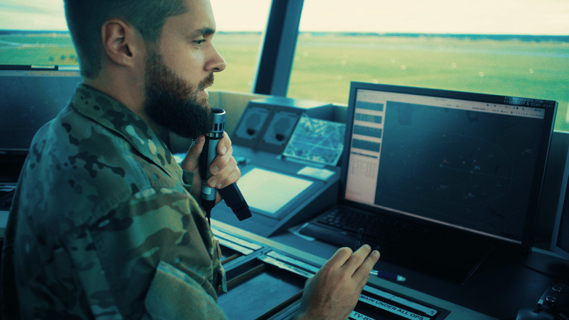 Flyveleder taler holder øje med skærmene på sin kontorplads på en flyvestation