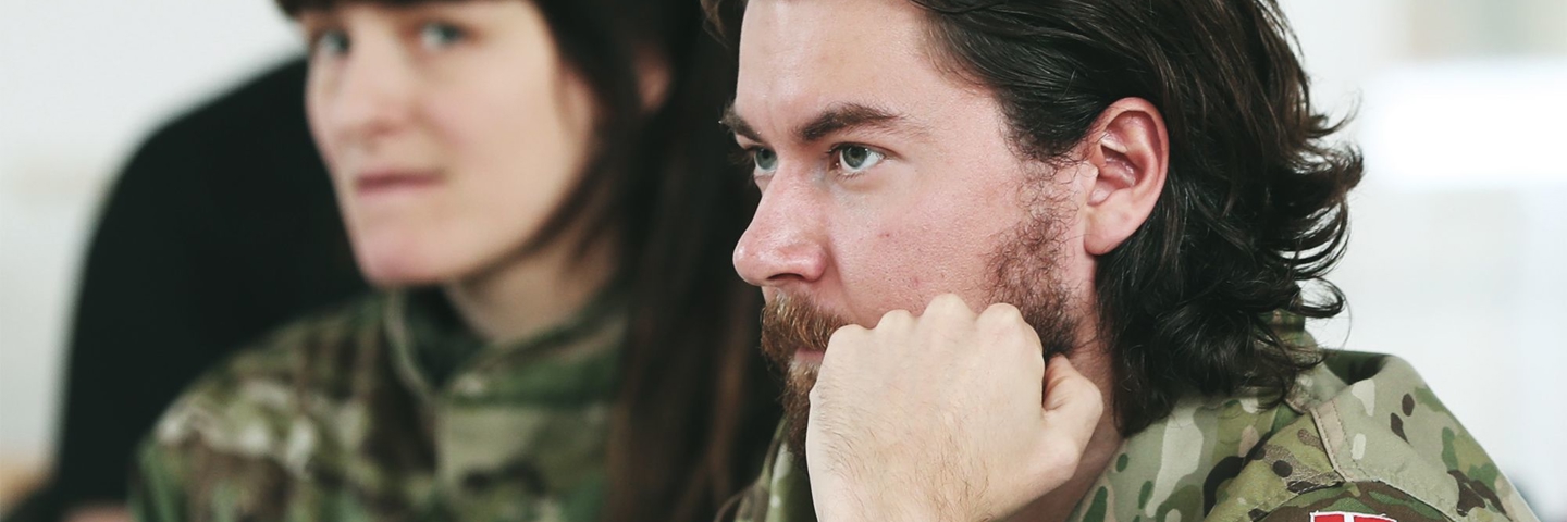 Soldat sidder ved bord med hånde under hagen
