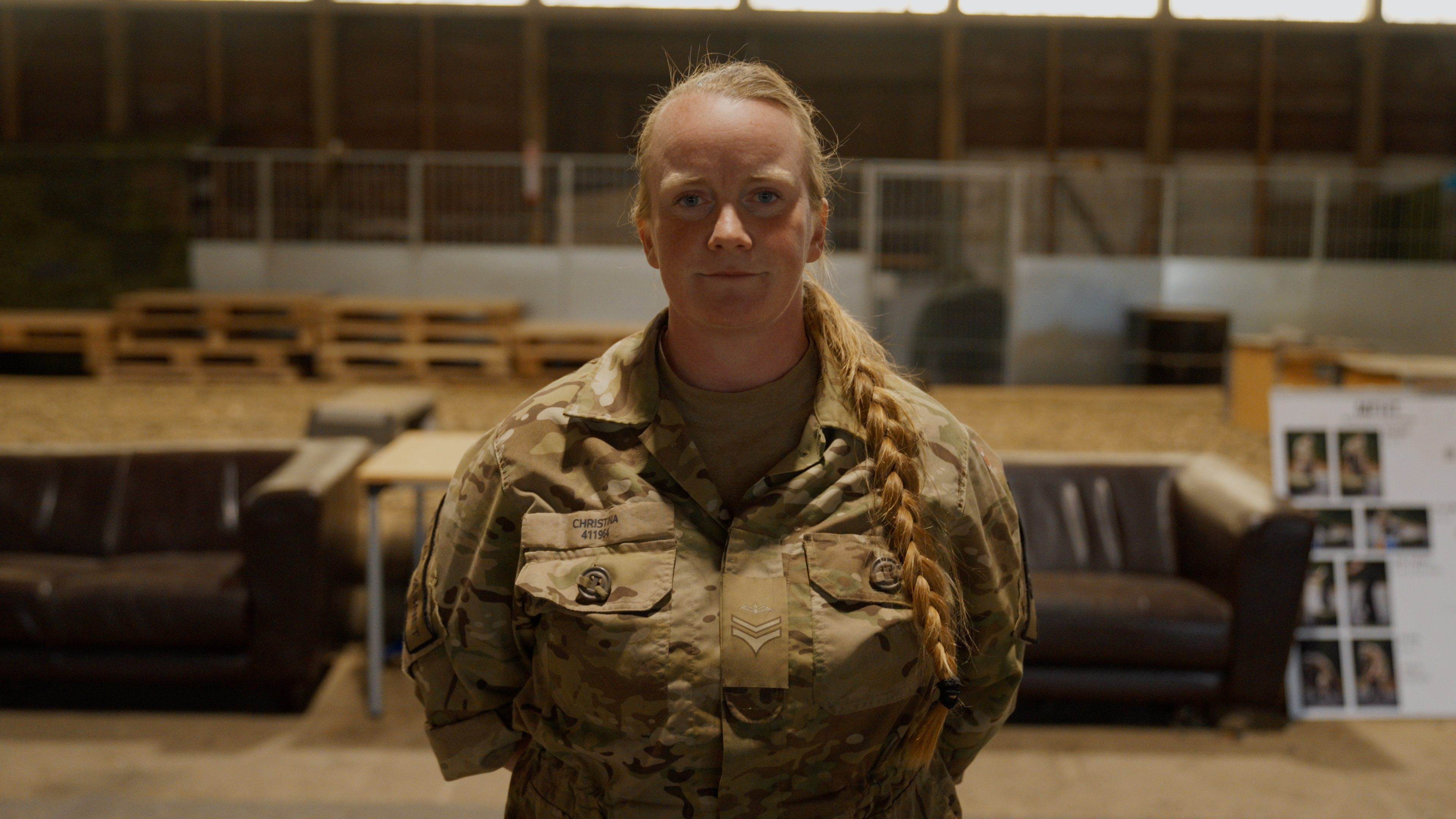 Hundetræner Christina står med armene på ryggen, smiler og kigger ind i kameraet