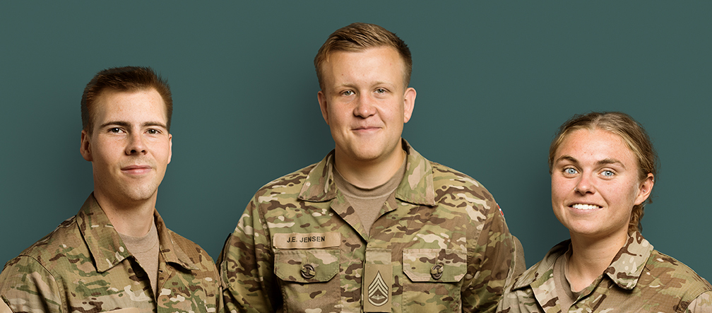 Tre soldater står med front mod kameraet og smiler