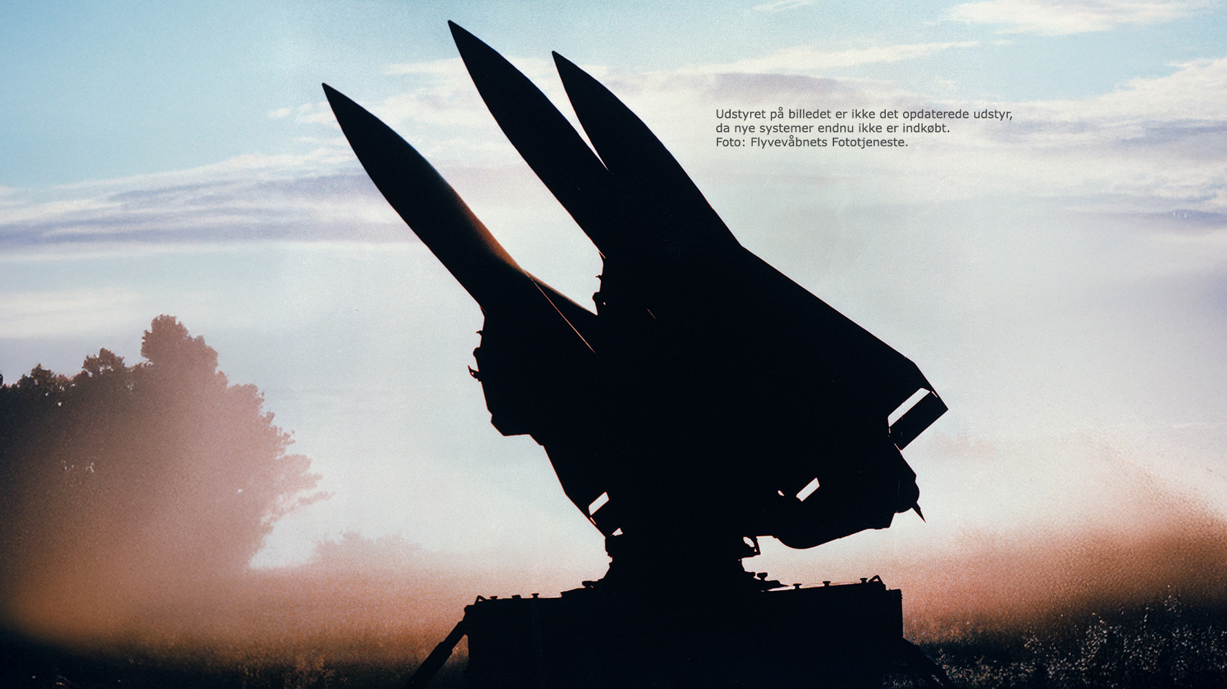 Silhuet af ældre missilsystem i solnedgang med tekst der oplyser, at udstyret ikke er opdateret. Foto: Flyvevåbnets Fototjeneste.