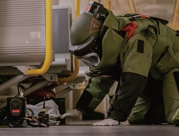 Ammunitionsrydder fra Forsvaret arbejder i metroen iført beskyttelsesdragt.