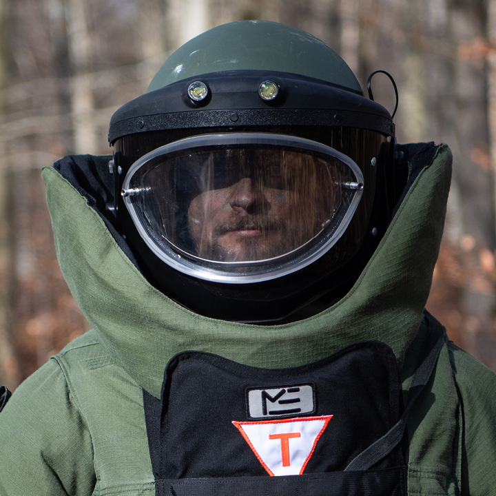 Person iført tung beskyttelsesdragt under ammunitionsrydning i Forsvaret