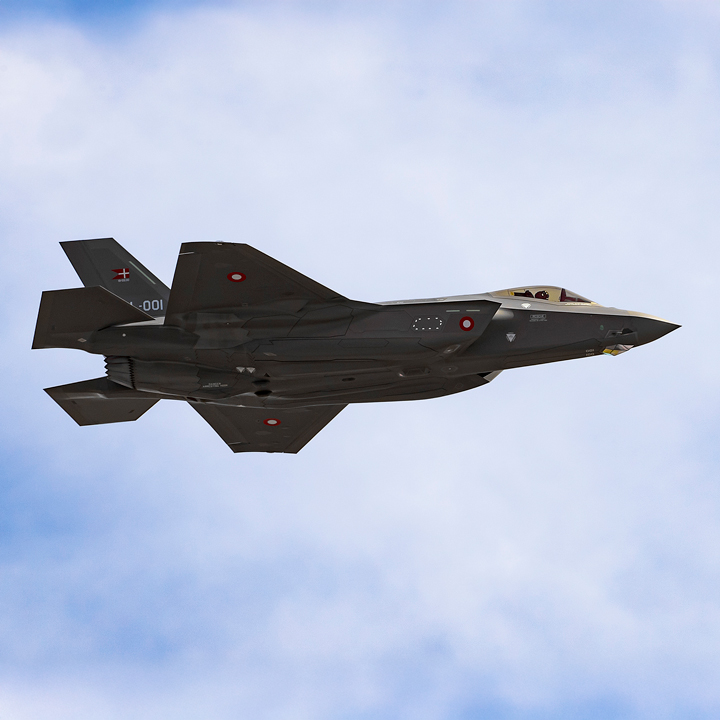 F35 kampfly i luften med blå himmel og hvide skyer.