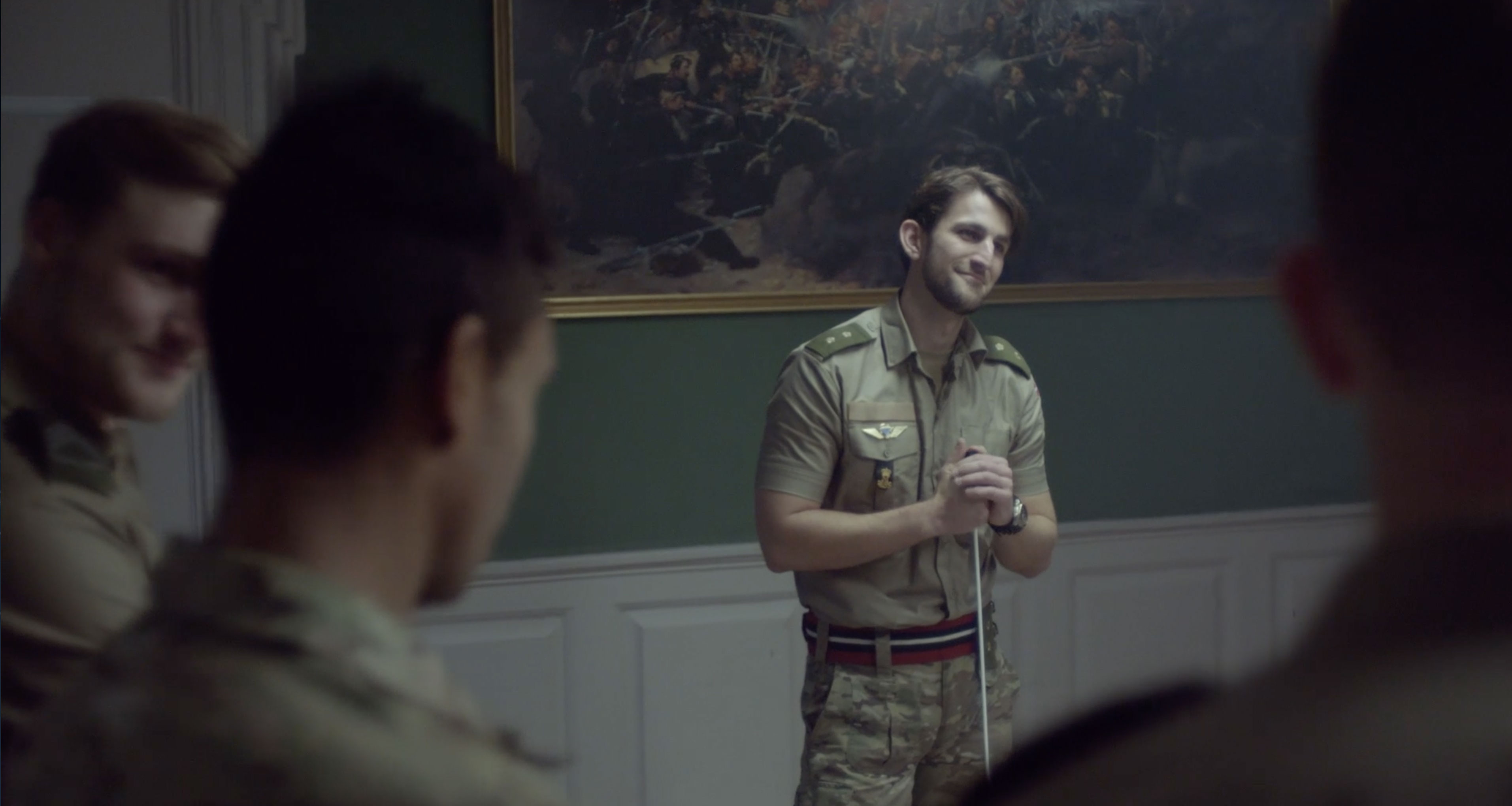 En officer taler til en gruppe soldater i et undervisningslokale.