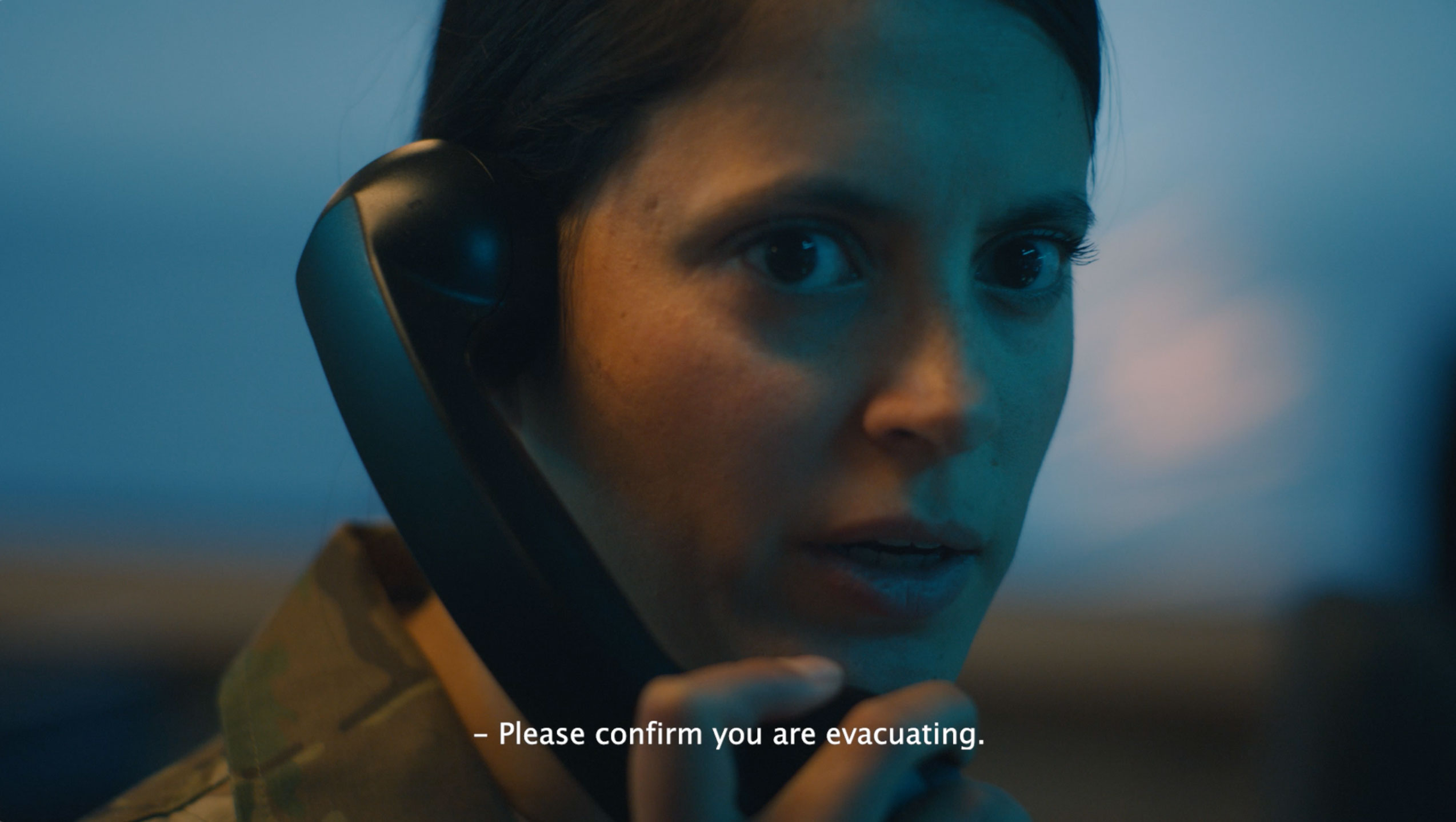 Kvinde i militæruniform taler i telefon med alvorligt udtryk