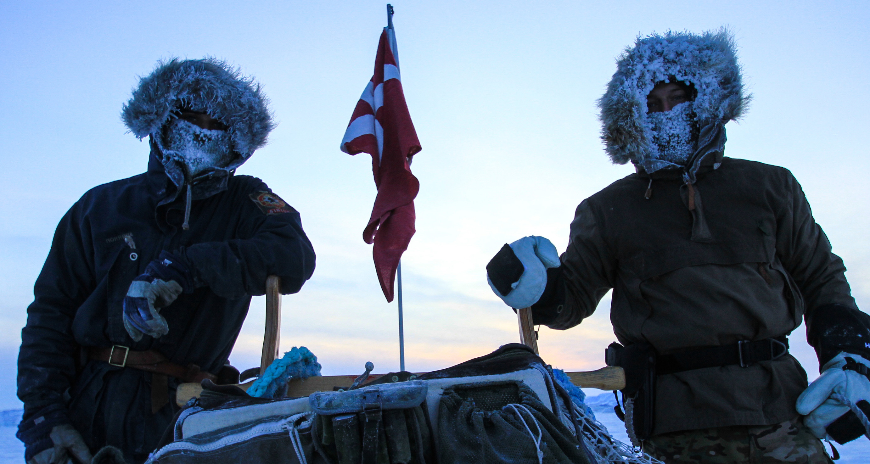 To fra Siriuspatruljen sidder i et sneklædt landskab.