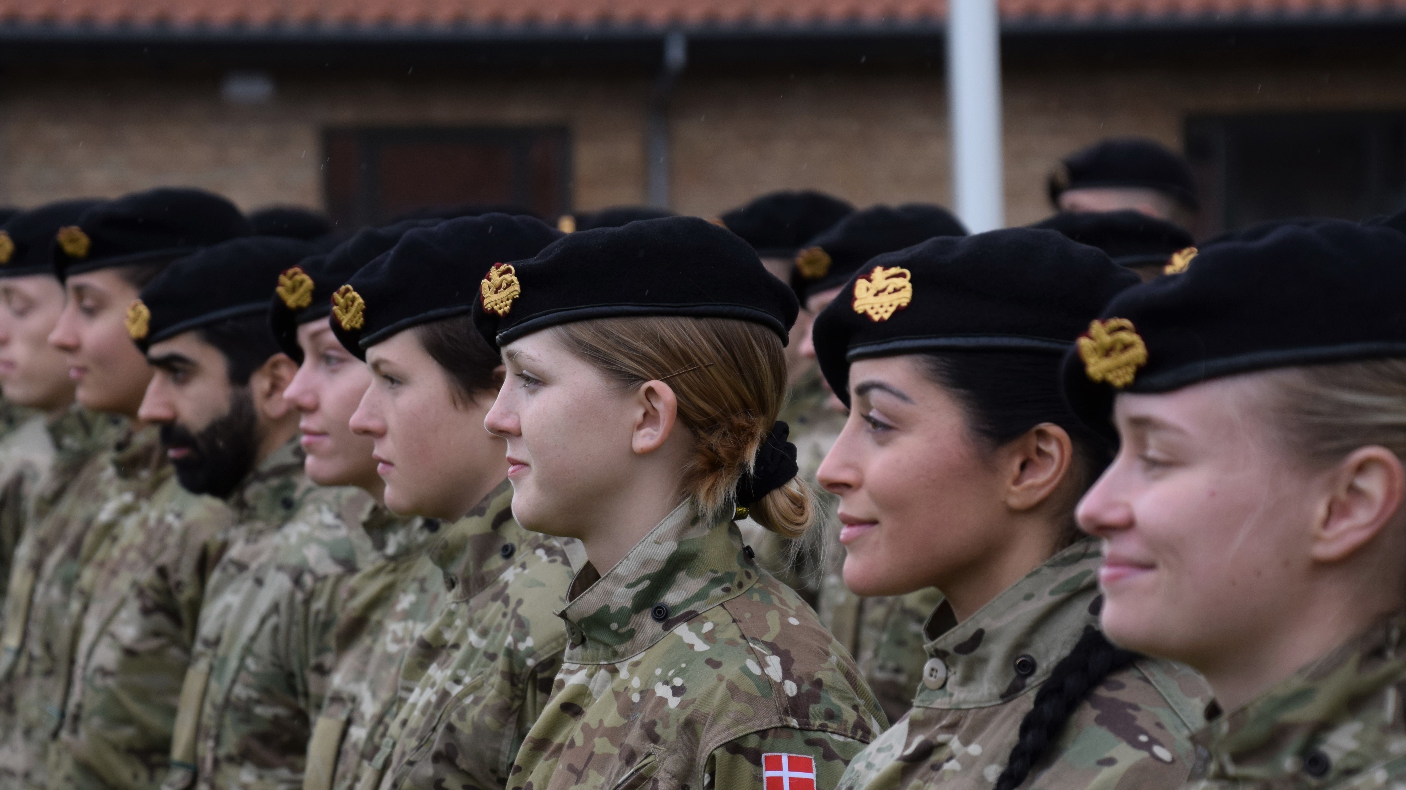 Danske soldater i uniform og baret står i formation.